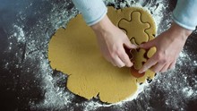woman hands cut gingerbread man cookies from raw dough using cutter top view