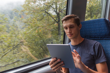 Young man studying with a tablet while travelling by train