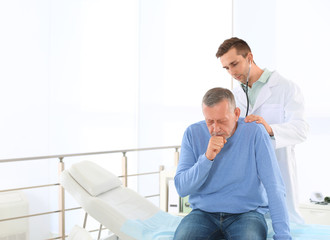 Canvas Print - Doctor examining mature patient with stethoscope in hospital. Space for text