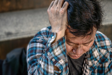 suffering asian poor homeless man sitting on pathway looking sad