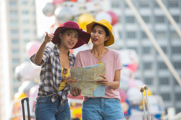 Two Tourist girl With drag bag Viewing map on the BTS station.
