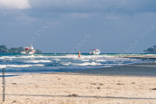 Fotografie, Obraz Caucasian woman, mid 40s, wearing two piece swimsuit walking into the ocean on S