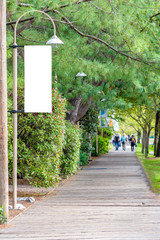 blank white isolated vertical banner flag mockup signage on a streetlight. public nature park walkwa