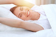 © rogerphoto - Beautiful young and happy woman stretching hands while lying in bed comfortably and blissfully smiling befor wake up in a morning. Sleeping concept