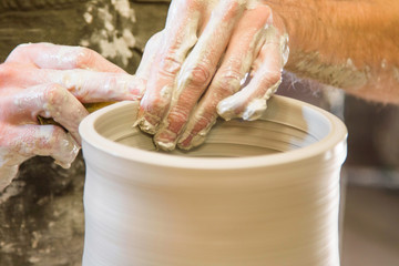      Artist potter in the workshop creating a ceramic vase. Hands closeup. Twisted potter's wheel. Small artistic craftsmen business concept. 