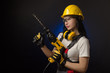 © rotozey - brunette girl in special clothes and a worker in a helmet posing on a black background with a working tool