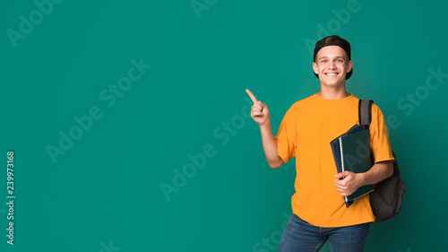 Fotomural Teen student with books pointing on copy space