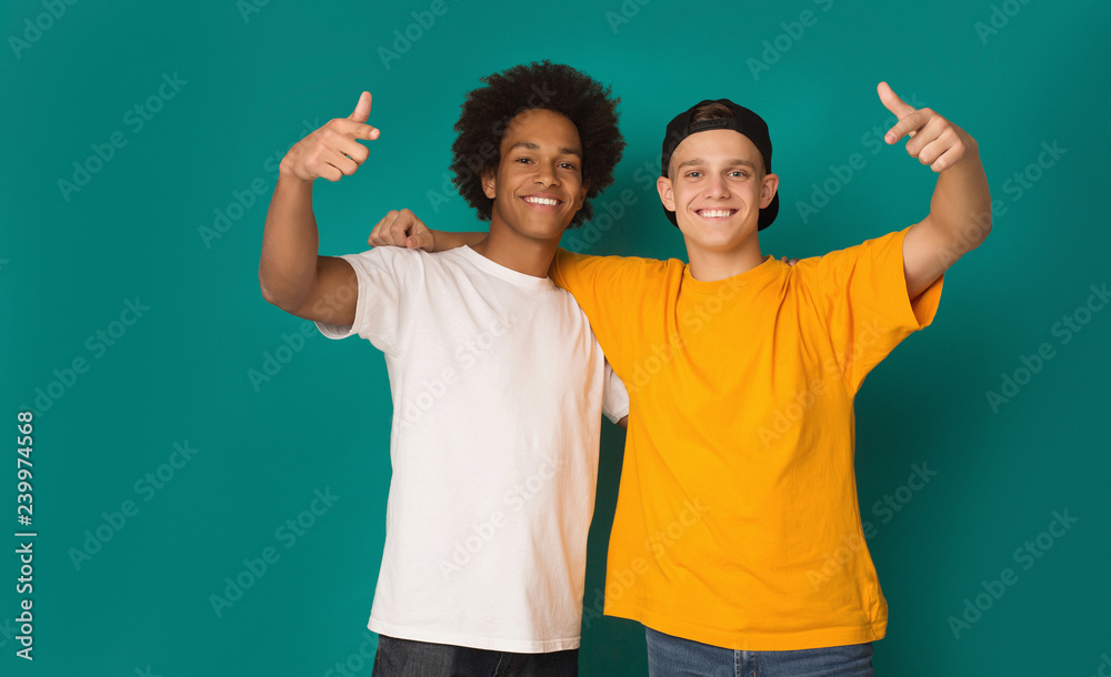 Portrait of two happy friends pointing fingers at camera - obrazy, fototapety, plakaty 
