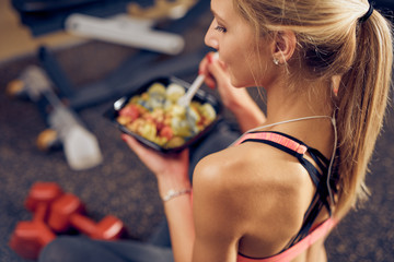 Top view of woman eating healthy food while sitting in a gym. Healthy lifestyle concept.