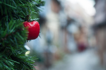 closeup of mini decorative red apple in christmas tree in the street