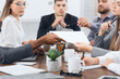 © Prostock-studio - Manager passing documents to his colleagues at meeting