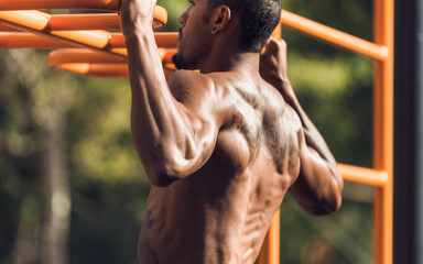 Muscular man doing pull up on horizontal bar