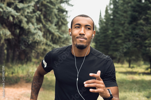 Fotografiet African-american man jogging and listening music outdoors