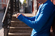 © Westend61 - Close-up of athlete leaning against house wall using cell phone