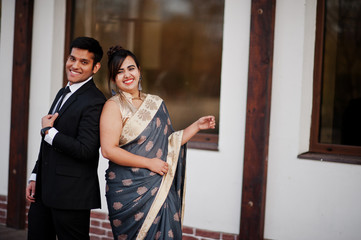 Wall Mural - Elegant and fashionable indian friends couple of woman in saree and man in suit.