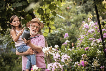 Grandfather and graddaughter taking care of flower bed