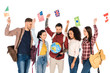© LIGHTFIELD STUDIOS - multiethnic group of people standing with backpacks and looking at globe while holding flags of different countries above heads isolated on white
