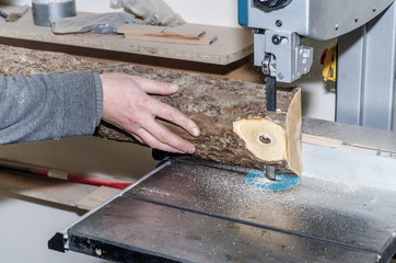 Poster - Worker in the carpentry workshop cuts the log into boards using a band saw. Joinery. Raw wood Wooden crafts. Work at the factory.