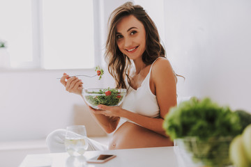 Wall Mural - Expectant mother tasting salad and holding big bowl in hands