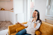 © bnenin - Happy young woman talking on the smart phone at home.