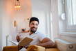 © bnenin - Young african american man enjoying free time at home. Reading a book and drinking coffee.