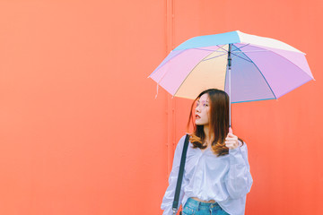 Wall Mural - Asian woman with colorful umbrella on red wall background.