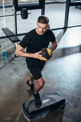 Wall Mural - high angle view of handsome sportsman training on step platform with medicine ball in gym