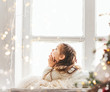 Cute little girl laying on windowsill on Christmas. Bright happy Christmas picture.