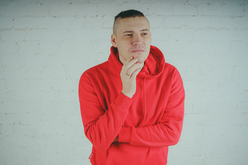 Wall Mural - Handsome guy posing by a brick wall. Crazy man in a red hoodie