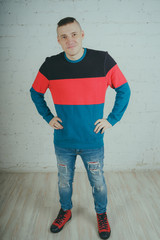 Wall Mural - Handsome guy posing against a brick wall. Crazy man in striped sweatshirt