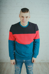 Wall Mural - Handsome guy posing against a brick wall. Crazy man in striped sweatshirt