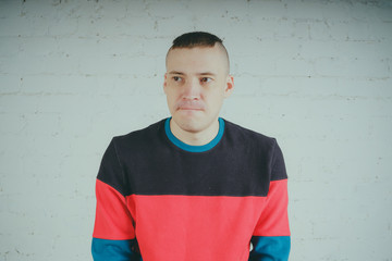 Wall Mural - Handsome guy posing against a brick wall. Crazy man in striped sweatshirt