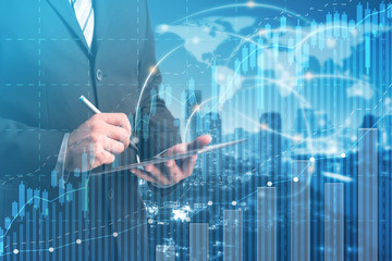 Poster - Double exposure businessman hold tablet PC on night city landscape background with Business Graph.Financial and business concept