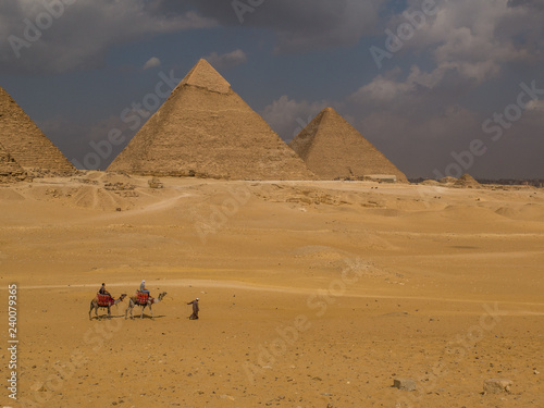 Fotografia, Obraz Arabic man with two camels in front of the Great Pyramids