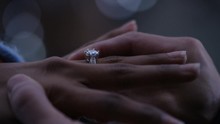 Male hand putting a ring on his partner's finger as he proposes, in slow motion 