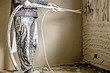 Worker applying gypsum plaster to the aerated concrete wall with a spray plastering machine.  Internal finishing in procces