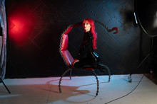 Dangerous Cruel Fetish Girl With Red Hair Posing In Black Bdsm Latex Clothes At The Chair From The Chains In The Style Of Sadomasochism