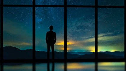 Wall Mural - The man standing near panoramic window on a starry sky background. time lapse