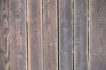 Wall Mural - Close-up of natural old vintage weathered gray brown unpainted solid wooden fence or gate of planks and boards. Ecological texture vertical copy space sunny crackled background.