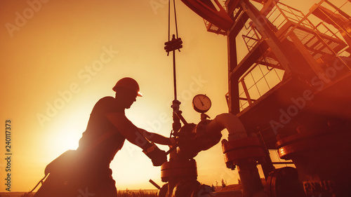 Cuadros en Lienzo Oil worker is checking the oil pump on the sunset background.