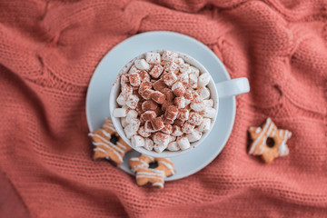 Wall Mural - Coffee cup with marshmallow and stars cookies on warm knitted coral blanket.