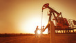 Leinwandbild Motiv Oil worker is checking the pump near oil derrick on the sunset background.