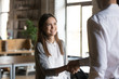 © fizkes - Excited girl intern handshaking executive manager getting hired rewarded, happy young employee proud to be promoted shake hands with boss congratulating successful worker, respect recognition concept