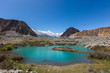 Panorama shot of small turquoise mountain lake under the sunny day with blue sky along Karakorum Highway in Passu, Hunza district of Pakistan.