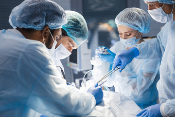 Poster - Concentrated Surgical team operating a patient in an operation theater. Well-trained anesthesiologist with years of training with complex machines follows the patient throughout the surgery.