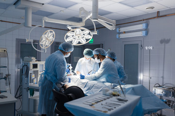 Poster - Multiracial Team of Surgeons concentrating on a patient during a heart surgery at a hospital. Mature caucasian doctor sharing his experiences with multiethnic colleagues.