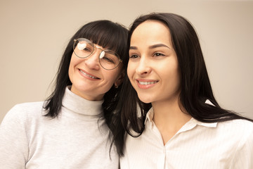 Wall Mural - A portrait of a happy mother and daughter at studio on gray background. Human positive emotions and facial expressions concept