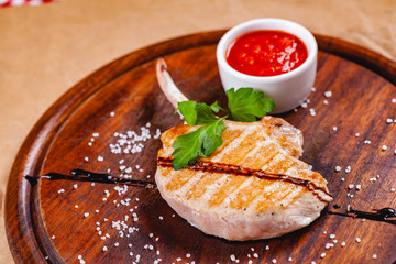 Wall Mural - Rack of lamb with tomato sauce on wooden cutting board. Close up