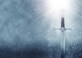 Wall Mural - mysterious and magical photo of silver sword over gothic snowy black background. Medieval period concept.