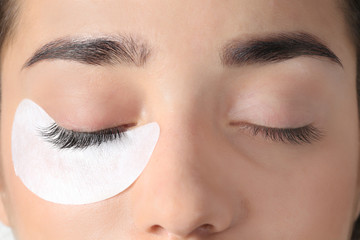 Poster - Young woman undergoing eyelashes extensions procedure, closeup